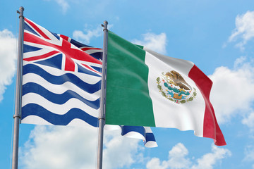 Mexico and British Indian Ocean Territory flags waving in the wind against white cloudy blue sky together. Diplomacy concept, international relations.