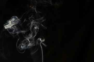 Abstract puffs of smoke on the left side of the frame on a dark background with a place for text, mysticism, fantasy