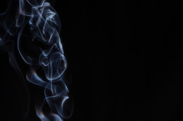 Obraz premium Abstract puffs of smoke on the left side of the frame on a dark background with a place for text, mysticism, fantasy