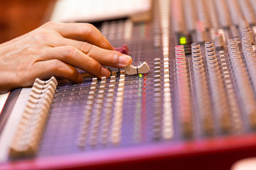 male sound engineer, dj hand working on audio mixing console. music production, post production,...