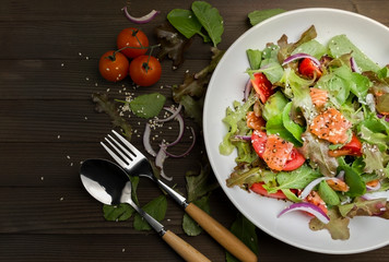Fresh salmon salad with tomatoes Fresh green onions and vegetables On a black background
