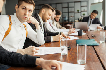 serious confident men in suits sit in office coworking, making notes, using papers. discuss and write business ideas