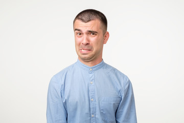 Funny young hispanic man showing cynical unhappy angry face