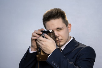 Portrait of a young man in a suit with an old camera, perhaps he is a novice journalist doing a report, a diplomat or secret agent photographing documents, a businessman collecting dirt