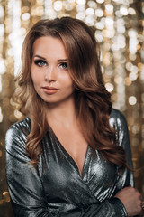 shiny woman in a silver dress on a gold background