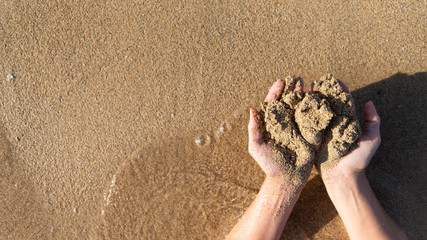 Sand in palms of women hands, top view. Relax on the sea beach, summertime. Rest in a sea resort. Hot summer background with copy space.
