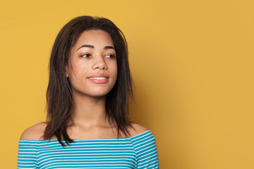Happy black woman smiling on yellow background