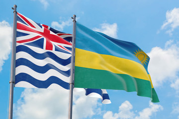 Rwanda and British Indian Ocean Territory flags waving in the wind against white cloudy blue sky together. Diplomacy concept, international relations.