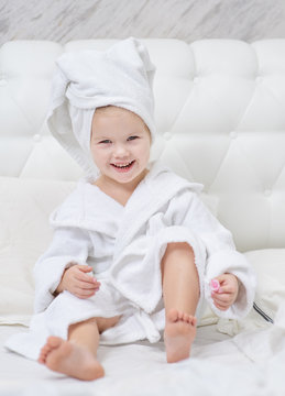 Little cute girl with a towel on her head does a manicure in her bedroom