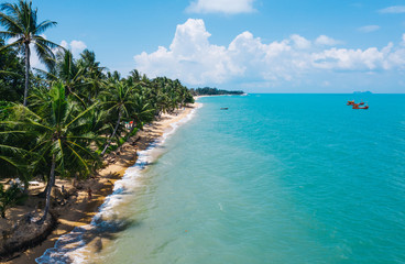 Aerial scenery view of white sand beach shore with turquoise clear sea water and foamy waves. Bird's eye panoramic view of picturesque coastline bay with fishermen boats. Samui island, Thailand