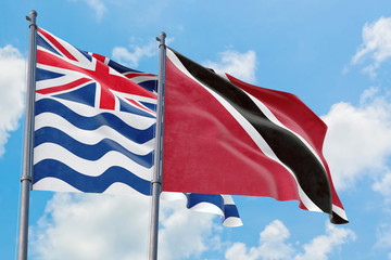 Trinidad And Tobago and British Indian Ocean Territory flags waving in the wind against white cloudy blue sky together. Diplomacy concept, international relations.