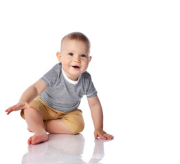 Happy smiling infant boy toddler in t-shirt and pants is start crawling going to on all fours on white with copy space 