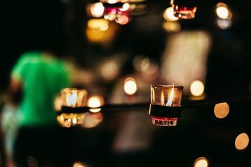 A Burning Candle in Clear Glass stick with steel rod Decorated in Hotel, Restaurant or Home. Selective Focus, Blurred Background with Bokeh.
