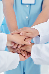 Close-up image of healthcare workers stacking hands to support each other befor long day of work