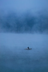 A fisherman in the morning mist on a lake