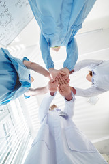 Group of pulmonology department medical workers stacking hands before starting long day of work