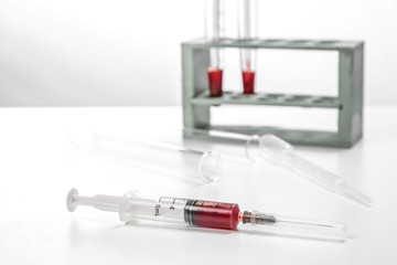 a sterile syringe with a blood sample on a white medical table. selective focus and small focus area