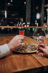 young people are sitting in a cafe eating sandwiches and drinking wine