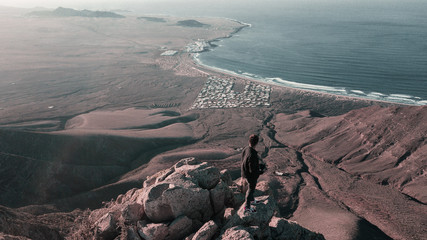 Man on top of the mountain looking to the beach Famara in Lanzarote, Canary Island