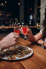 young people are sitting in a cafe eating sandwiches and drinking wine