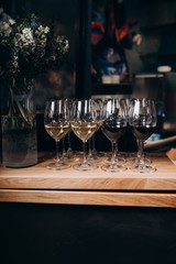 glasses of white and red wine stand on the bar in the restaurant next to flowers