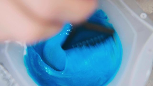 The hairdresser colorist mixes paint for hair dyeing. Close-up.