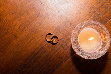 wedding rings and candle on wooden table