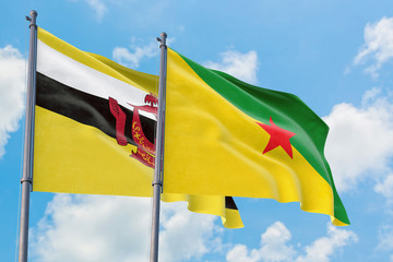 French Guiana and Brunei flags waving in the wind against white cloudy blue sky together. Diplomacy concept, international relations.