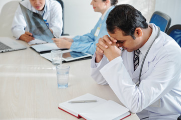 Fototapeta premium Stressed and tired physician sitting at table in doctors lounge