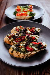 Italian Appetizer Bruschetta with roasted tomatoes, mozzarella cheese, garlic and herbs on wooden table