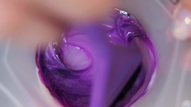 The hairdresser colorist mixes paint for hair dyeing. Close-up.