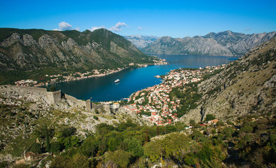 Fototapeta na wymiar Top view of Kotor bay and old town surrounded by rocks of mountains on blue sky