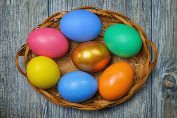 Fototapeta na wymiar Colorful Easter eggs in the basket on the brown wooden surface
