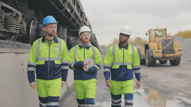 Three multicultural industrial experts walking on crushed stone extraction site