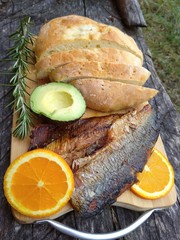 Clupea harengus, Atlantic herring slice of avocado, slice of orange and traditional bread in white plate