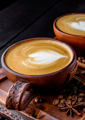 Two cups of cappuccino coffee with latte art on dark background