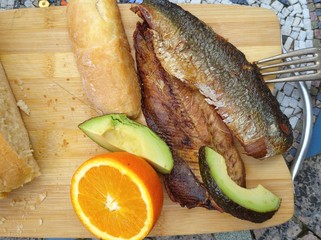 Clupea harengus, Atlantic herring slice of avocado, slice of orange and traditional bread in white plate