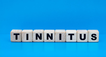 concept word tinnitus on cubes on a blue background