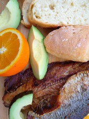 Clupea harengus, Atlantic herring slice of avocado, slice of orange and traditional bread in white plate