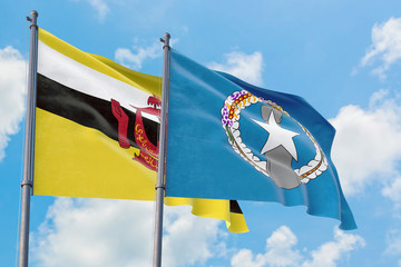 Northern Mariana Islands and Brunei flags waving in the wind against white cloudy blue sky together. Diplomacy concept, international relations.