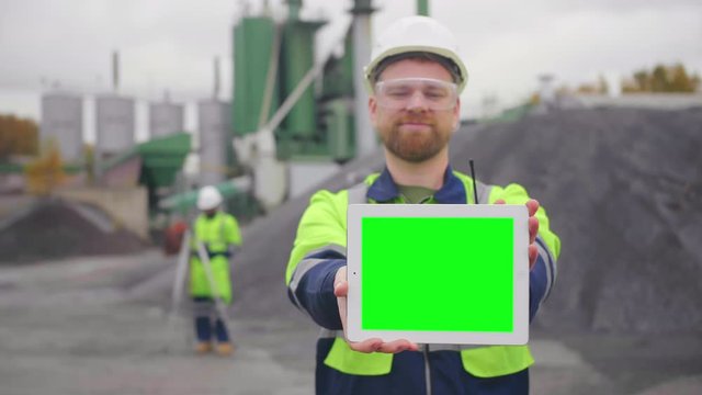 Young geodesist showing blank screen of tablet at camera and smiling.
