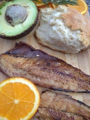 Clupea harengus, Atlantic herring slice of avocado, slice of orange and traditional bread in white plate