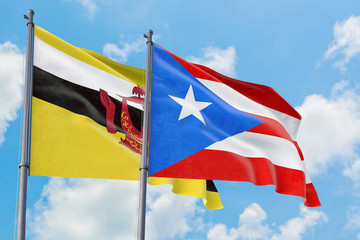Puerto Rico and Brunei flags waving in the wind against white cloudy blue sky together. Diplomacy concept, international relations.