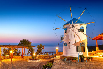 Fototapeta na wymiar Traditional Wind Mills in Greece, Zakynthos Island. Incredibly romantic sunrise on Zakinthos. Amazing sunset view on old mill with multicolored clouds. Old Windmill in Agios Nikolaos near blue caves.