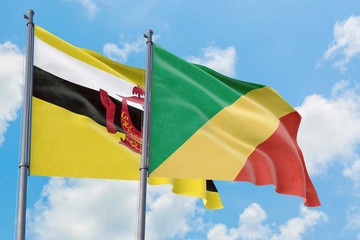 Republic Of The Congo and Brunei flags waving in the wind against white cloudy blue sky together. Diplomacy concept, international relations.