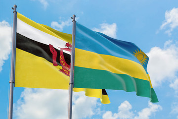 Rwanda and Brunei flags waving in the wind against white cloudy blue sky together. Diplomacy concept, international relations.
