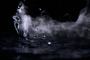 Boiling water splash with steam on black background closeup