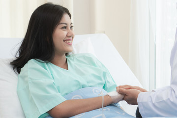 Doctor encouraging patient during treatment therapy and holding hands to support.