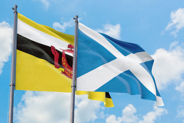 Scotland and Brunei flags waving in the wind against white cloudy blue sky together. Diplomacy concept, international relations.