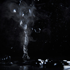 Boiling water splash with steam on black background closeup